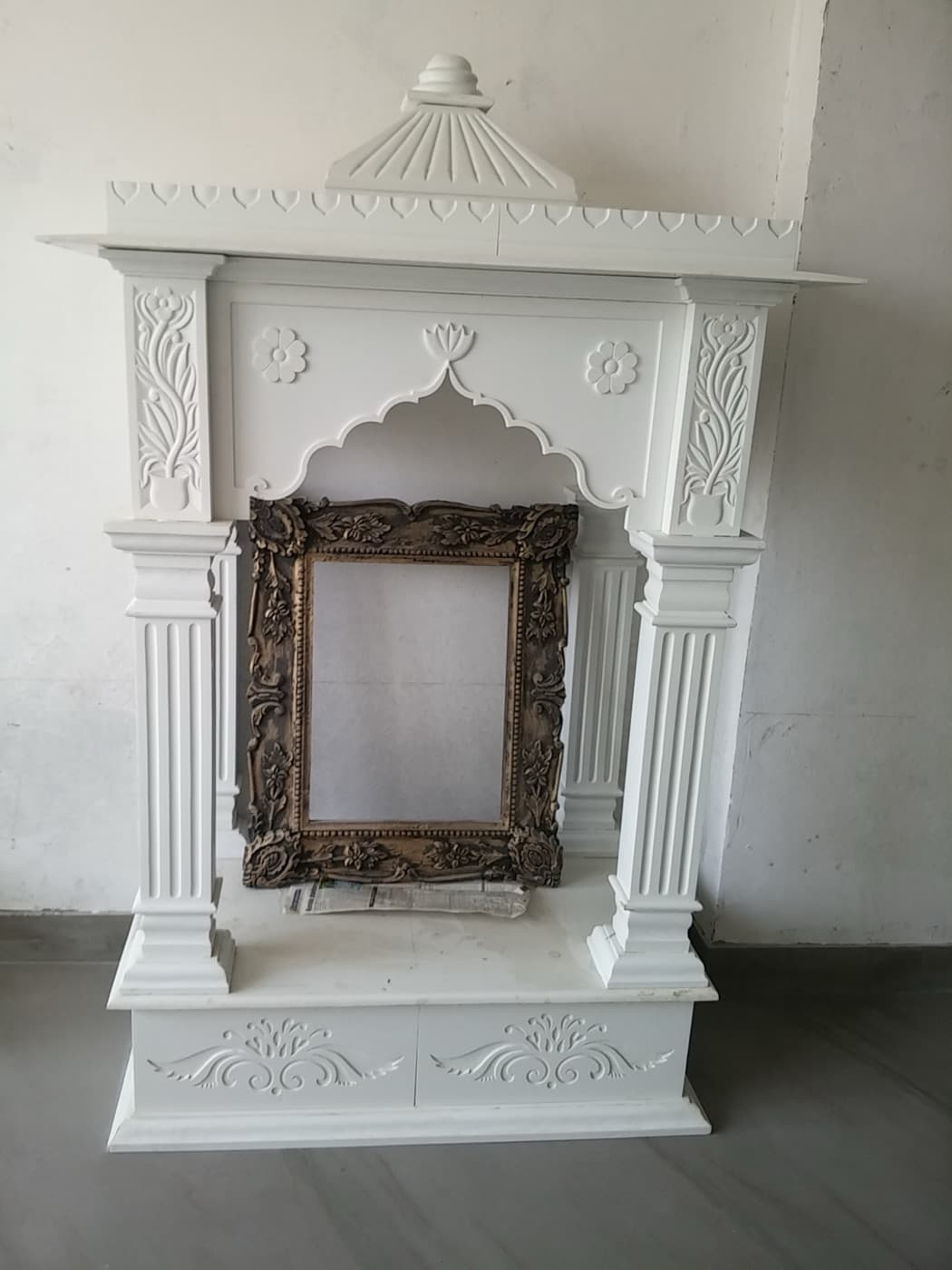 Marble mandir with fluted pillars, floral panels and scalloped arch