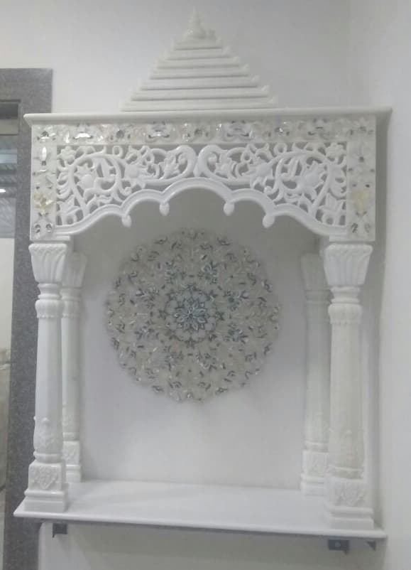 Wall-mounted marble mandir with jali canopy and inlay medallion