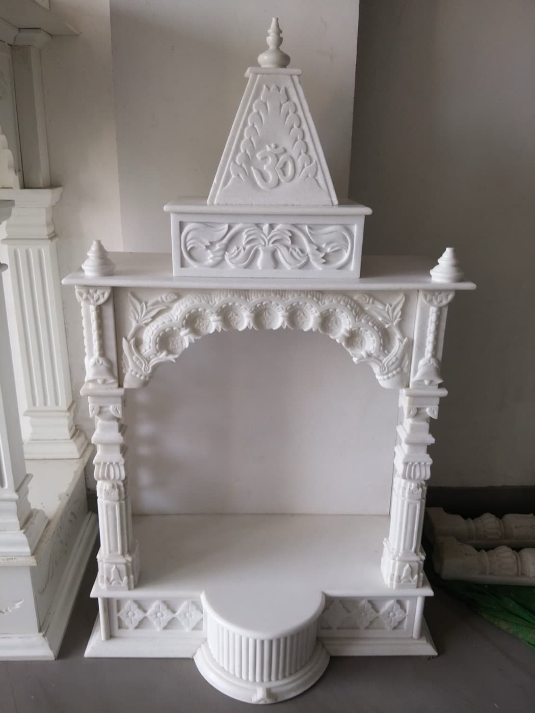 Marble mandir with Om shikhar, carved floral arch and fluted pedestal